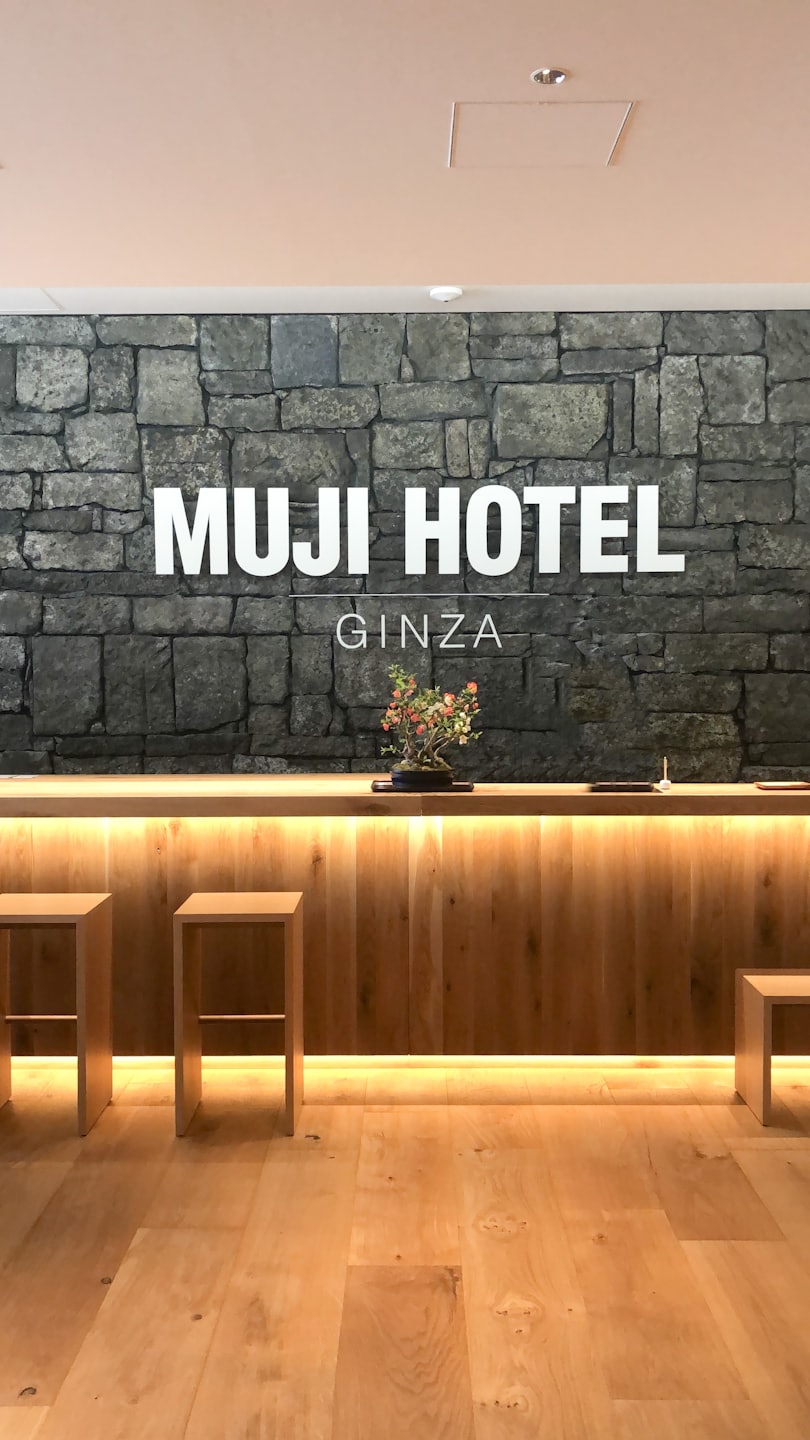 Mostrador de recepción de hotel con mostrador de madera y pared de piedra gris.