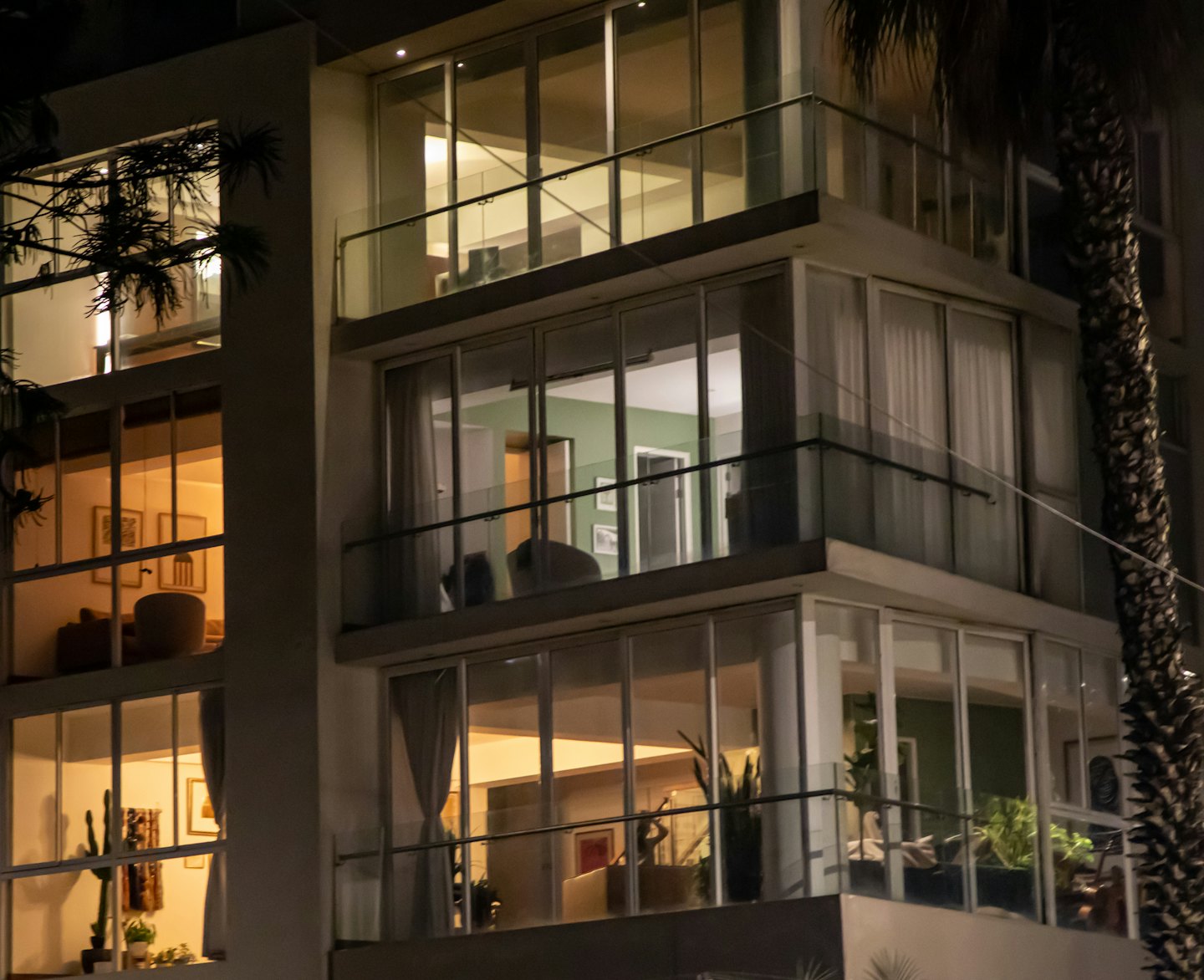Edificio de apartamentos moderno por la noche con interiores cálidamente iluminados.