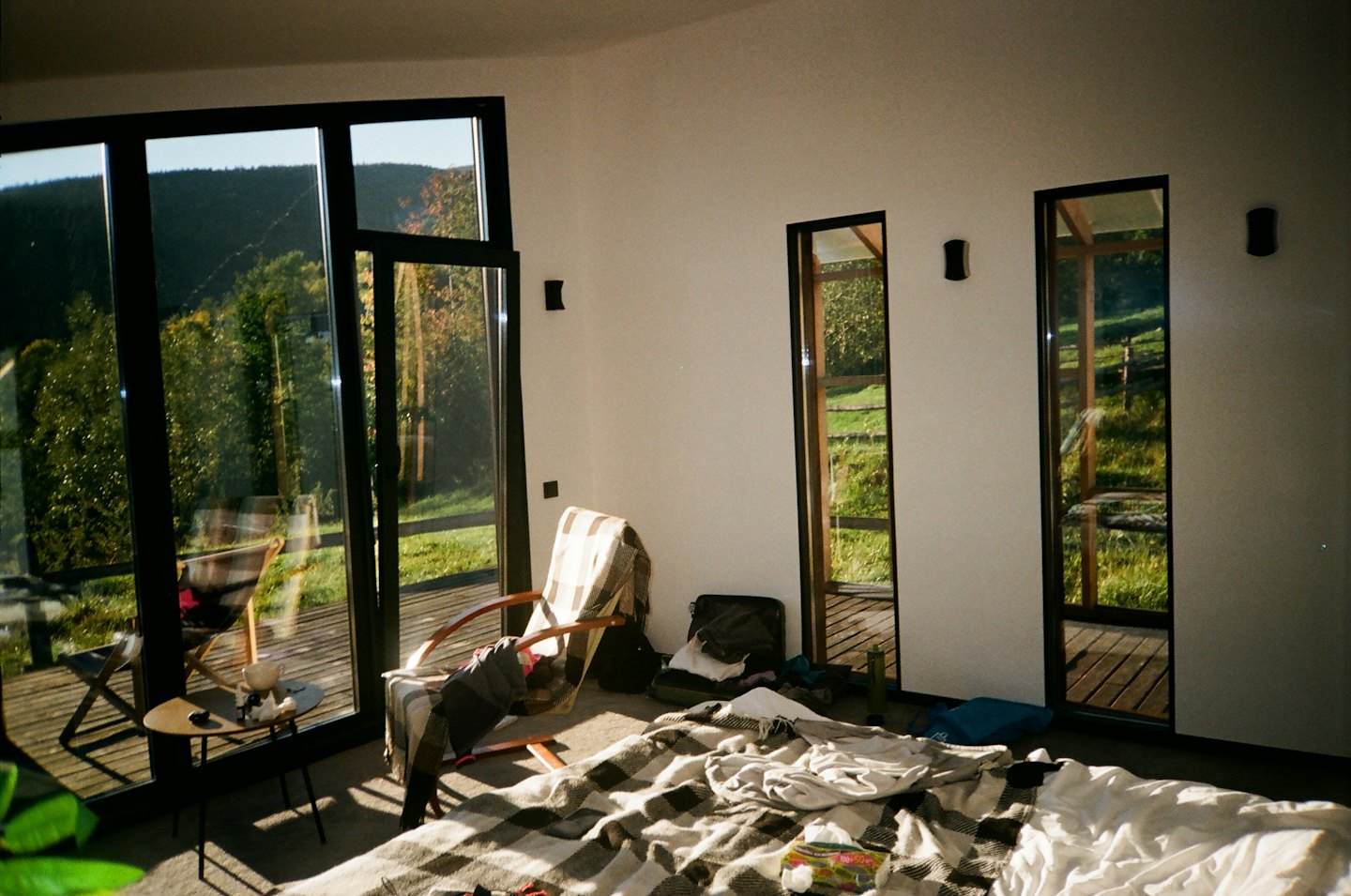Dormitorio moderno con manta a cuadros con vistas a un paisaje montañoso.