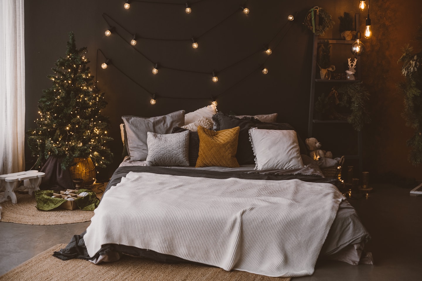 Árbol de Navidad decorado y cama con luces navideñas.